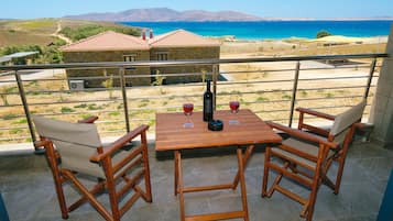 A wooden table with two chairs on a balcony overlooking a coastal landscape.