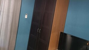 Een kamer met een donker houten garderobe, een televisie en een blauwe muur.