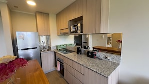 A compact kitchen with a refrigerator, sink, and countertop appliances.
