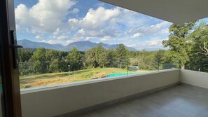 A balcony with a view of mountains, trees, and a grassy area. - Oceana Suites Meli Pucón (Pucon)