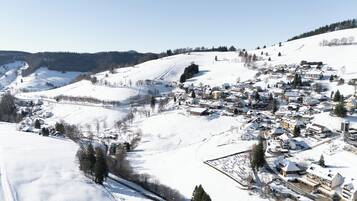 Un village enneigé, avec des bâtiments, une piste de ski et un ciel dégagé.