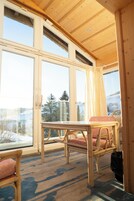 Una habitación con ventanas amplias, una mesa y dos sillas.