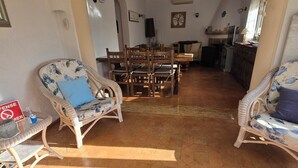 Una habitación iluminada por el sol, con suelo de baldosas hexagonales, muebles de madera y un comedor con mesa y sillas.