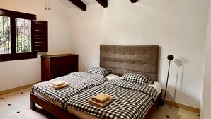 A bedroom with a bed, a nightstand, a window, and a ceiling fan.