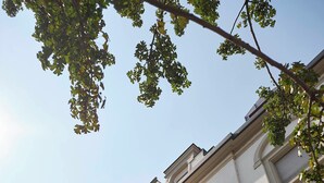 Ein Gebäude mit weißer Fassade, einem Balkon mit schwarzen schmiedeeisernen Geländern und einem blauen Himmel im Hintergrund.