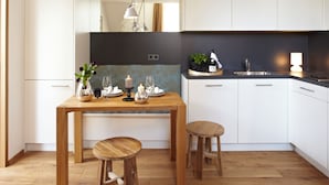 Eine moderne Küche mit einem Holztisch, zwei Hocker und einem Einbauofen.