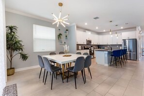 Een moderne keuken met witte kasten, een centraal eiland en blauwe barkrukken.