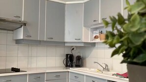 A modern kitchen with grey cabinets, a stainless steel range hood, and a built-in oven. - Aux Pieds des Tours (La Rochelle)