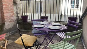 A small outdoor patio with a table set for four, surrounded by chairs and potted plants. - Aux Pieds des Tours (La Rochelle)