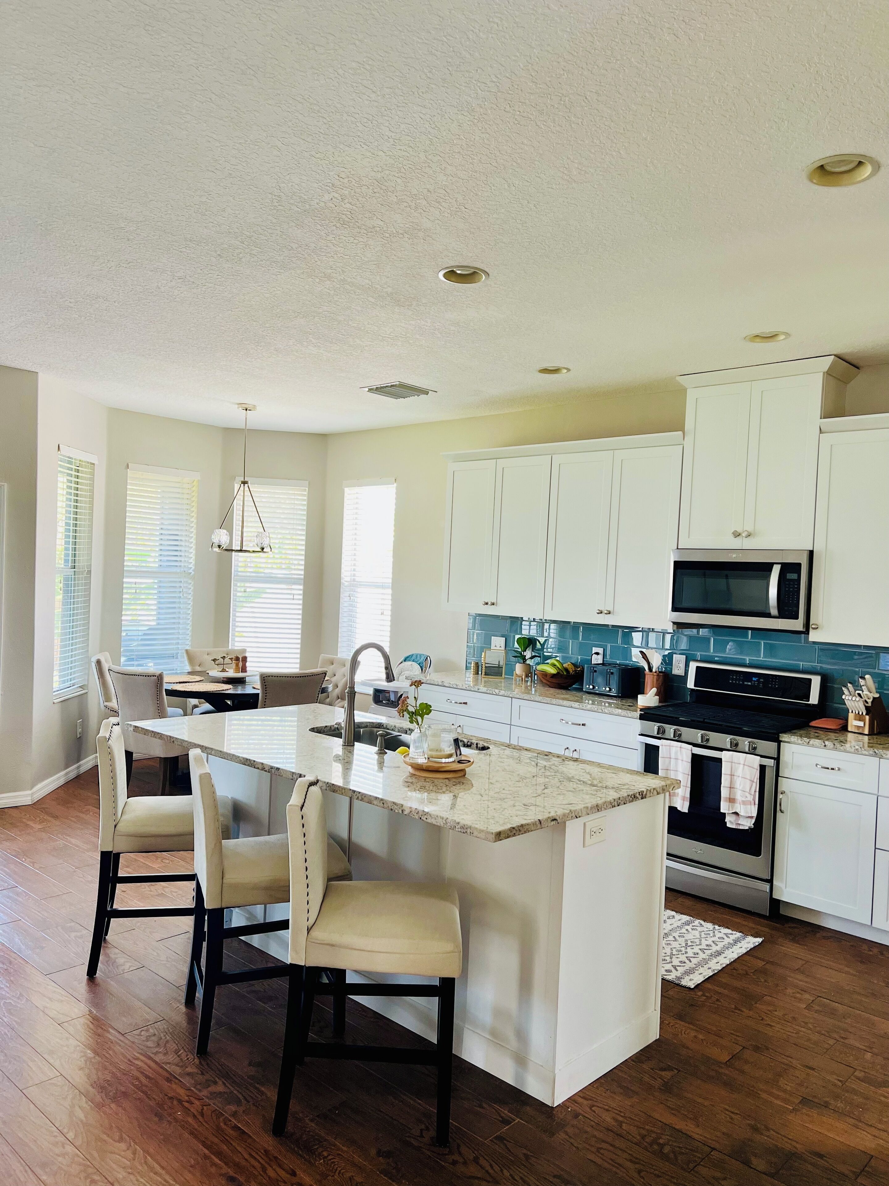 A modern kitchen with a central island, white cabinetry, a microwave, stove, and a sink.