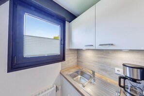 A compact kitchen with a window, stainless steel sink, and modern cabinetry.