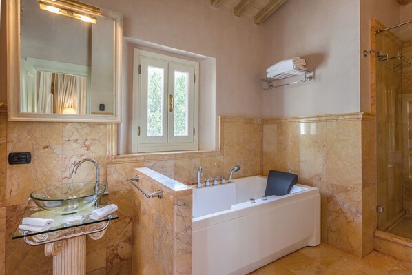 A bathroom with a glass bowl sink, a white bathtub, a mirror, and a window.