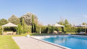 Una piscina con dos gazebos, uno con un sofá y otro con una mesa y sillas.