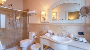 Un baño con ducha de vidrio, inodoro, bidé, lavabo con espejo y artículos de aseo.