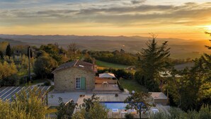 Uma casa de pedra com piscina, rodeada por árvores e colinas.