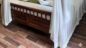 Ein Himmelbett mit Holzbalken und weißer Bettwäsche.