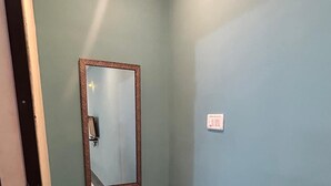 Ein kleines Badezimmer mit einem gemusterten Boden, einem Spiegel mit dekorativem Rahmen und einem Mülleimer.