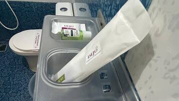 Ein Badezimmer mit Waschbecken, Toilette und Pflegeprodukten, darunter Deja Soapy Body Lotion und Deja Soapy Body Wash.