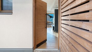 A hallway with wooden slats, a wooden door, and a view into a dining area with a table and chairs. - Apartment 'Villa Helena' with Mountain View, Private Terrace and Wi-Fi (Cavalese)