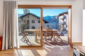 A room with a sliding glass door leading to a wooden deck with outdoor furniture, a mountain view, and a modern interior. - Apartment 'Villa Helena' with Mountain View, Private Terrace and Wi-Fi (Cavalese)