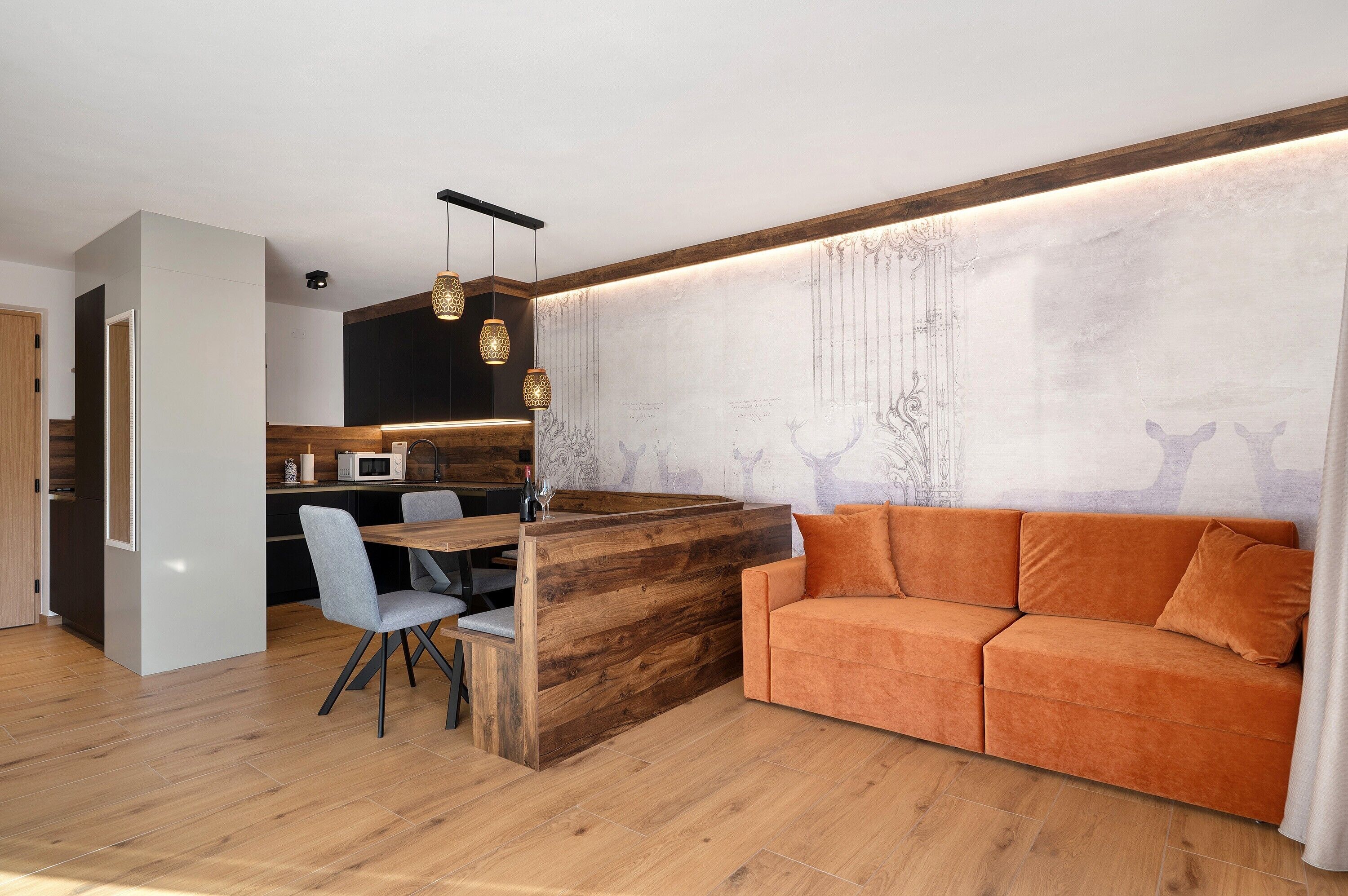 Una cocina moderna con una isla de madera, una zona de comedor con sillas y un sofá.