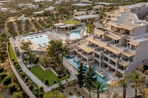 A modern hotel with multiple balconies, a swimming pool, and landscaped gardens.