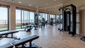 A spacious gym with various exercise equipment, large windows, and a view of the outdoors. - Kakkos Terra Blu (Ierapetra)