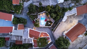 An aerial view of a residential area with multiple houses, a swimming pool, and a small garden area. - Traditional Villa w/ Pool & BBQ, near Rethymno (Atsipades)