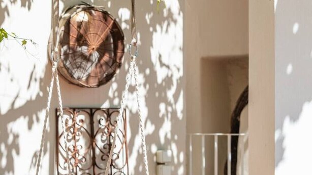 A hanging chair, a decorative metal wall piece, and potted plants in a sunny outdoor area. - Traditional Villa w/ Pool & BBQ, near Rethymno (Atsipades)