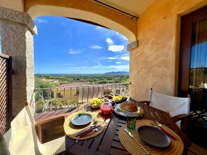 A balcony with a table set for breakfast, overlooking a scenic landscape. - Costa Blue Vacation Home (Agrustos)