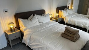 Une chambre d’hôtel avec un grand lit, deux tables de chevet et un miroir.