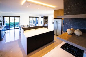 A modern kitchen with a large island, built-in appliances, and a stone fireplace.