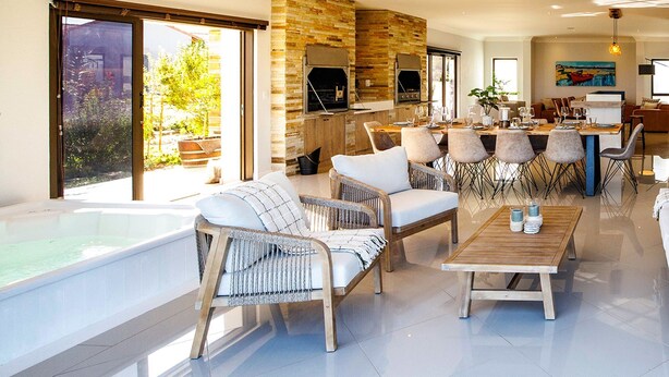 A spacious living area with a large window, a fireplace, and a dining area with multiple chairs. - 1160 Nagel Langebaan Country Estate (Langebaan)