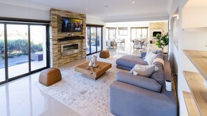 A modern living room with a grey sofa, wooden coffee table, and a stone fireplace. - 1160 Nagel Langebaan Country Estate (Langebaan)