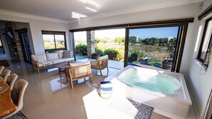 A spacious living area with a large window, a hot tub, and a dining setup. - 1160 Nagel Langebaan Country Estate (Langebaan)