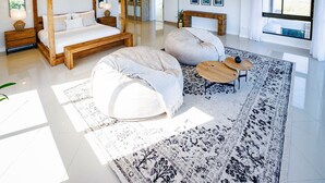 A spacious bedroom with a four-poster bed, two bean bags, a large rug, and a view of the outdoors through a large window. - 1160 Nagel Langebaan Country Estate (Langebaan)