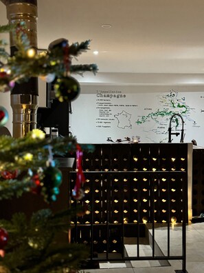 A room with a Christmas tree, a map on the wall, and a wine rack with bottles. - Masion de ville Champenoise (Épernay)