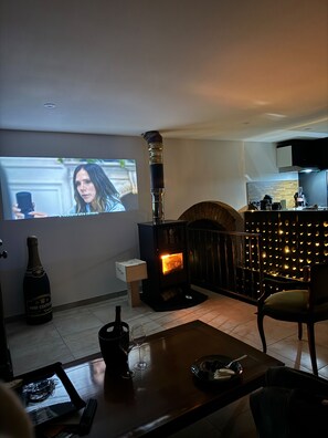 Ein Wohnzimmer mit Kamin, Fernseher und einer Weinflasche auf einem Tisch.
