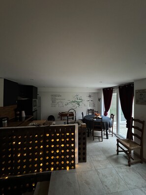 A modern kitchen with a dining area, a map on the wall, and a wine rack with lights. - Masion de ville Champenoise (Épernay)