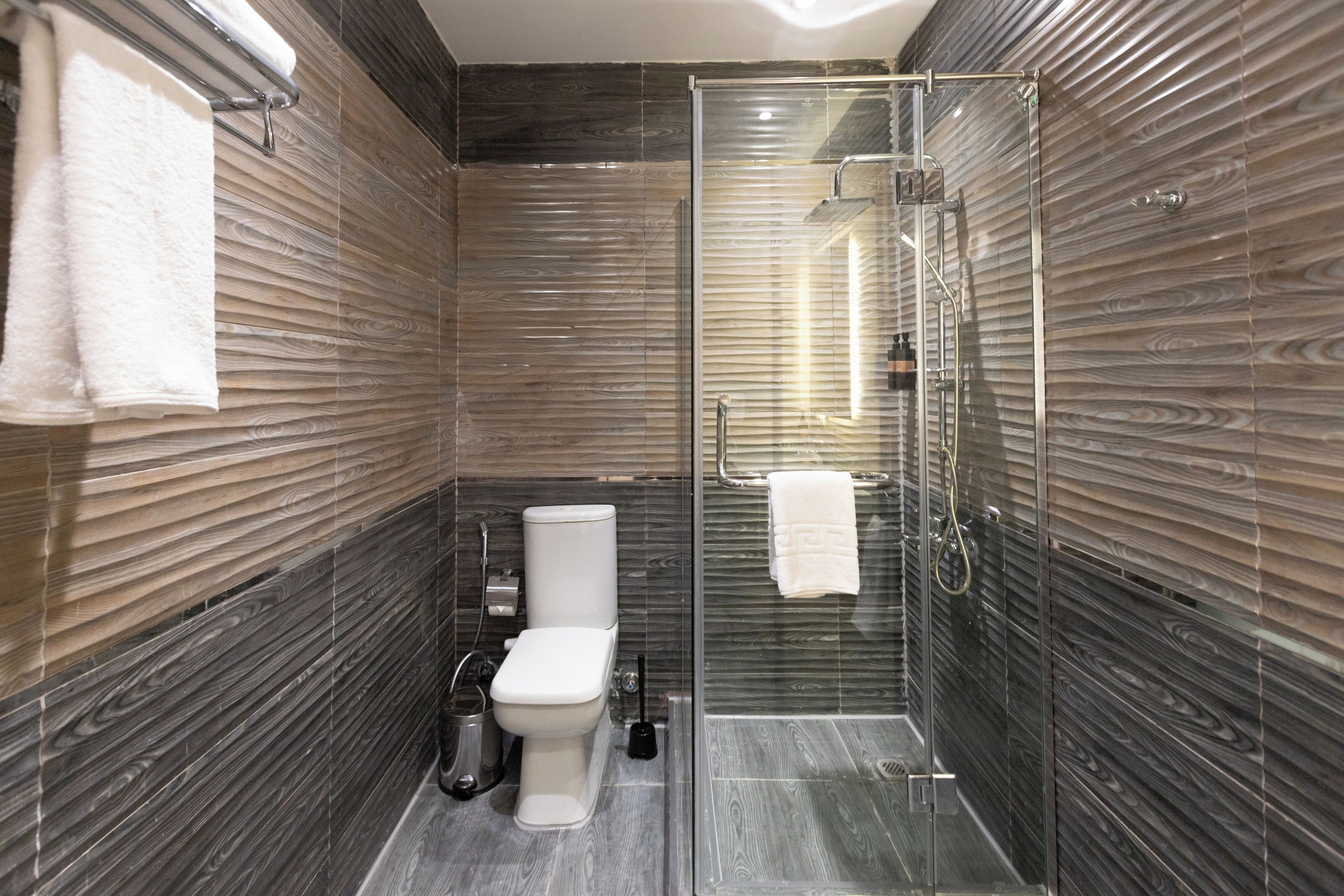 Une salle de bain moderne avec une douche à parois de verre, des toilettes et un porte-serviettes.