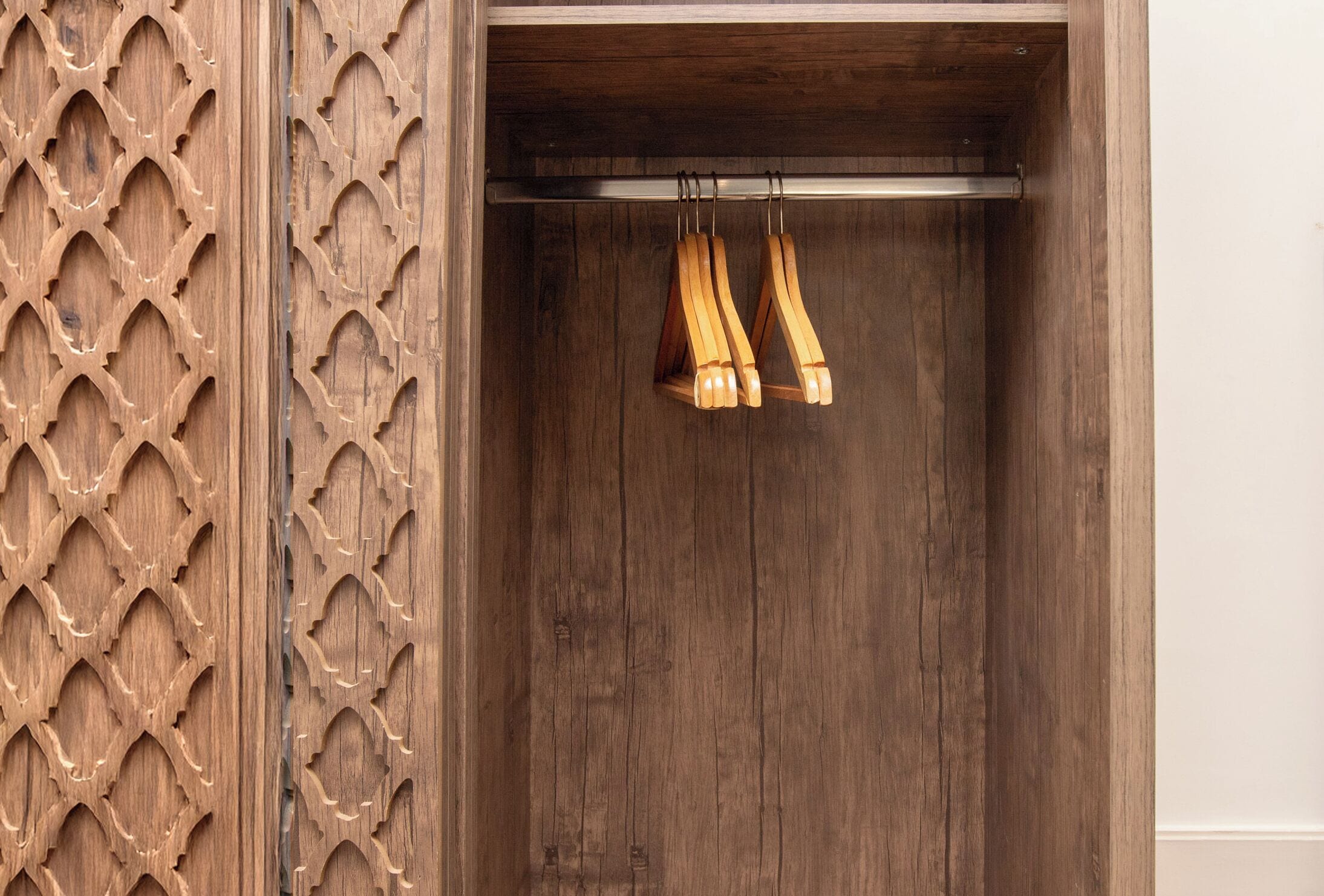 Une armoire en bois ornée d’un panneau décoratif et dotée de deux porte-manteaux en bois.