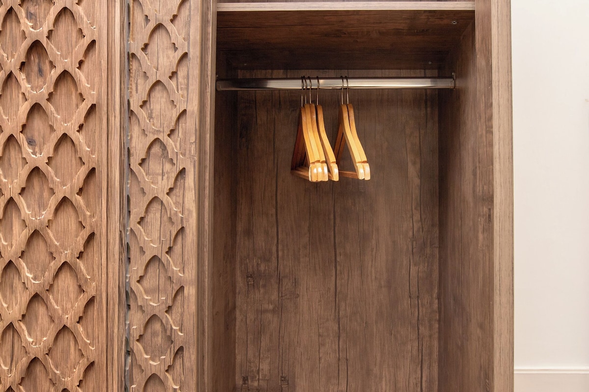 Une armoire en bois ornée d’un panneau décoratif et dotée de deux porte-manteaux en bois.