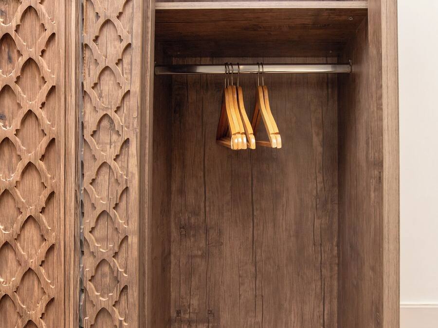 Une armoire en bois ornée d’un panneau décoratif et dotée de deux porte-manteaux en bois.