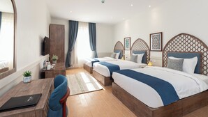 Une chambre d’hôtel avec deux lits, un bureau, une chaise, une télévision et une fenêtre avec des rideaux.