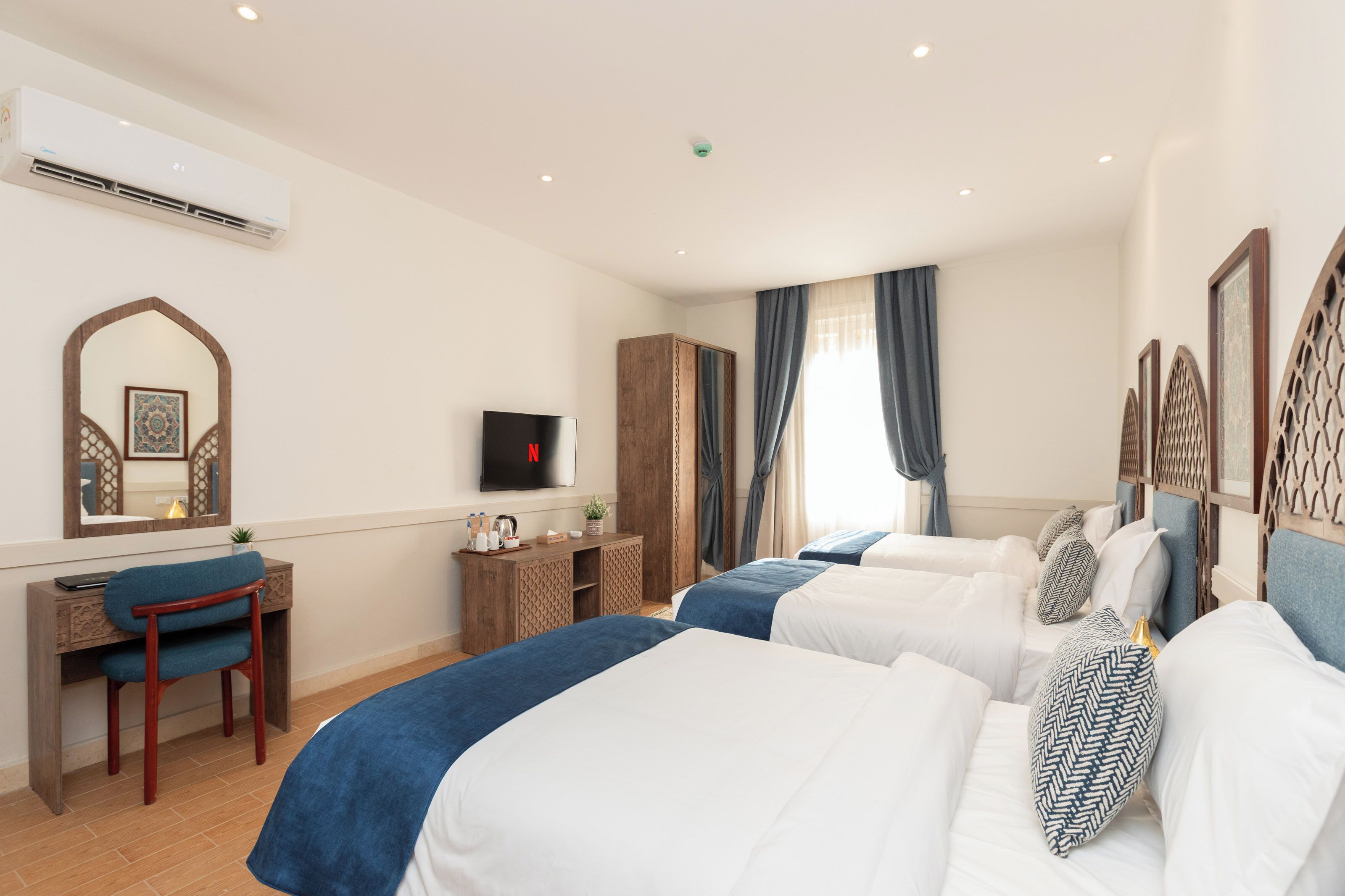 Habitación de hotel con dos camas, un escritorio, una silla, un televisor y un armario.
