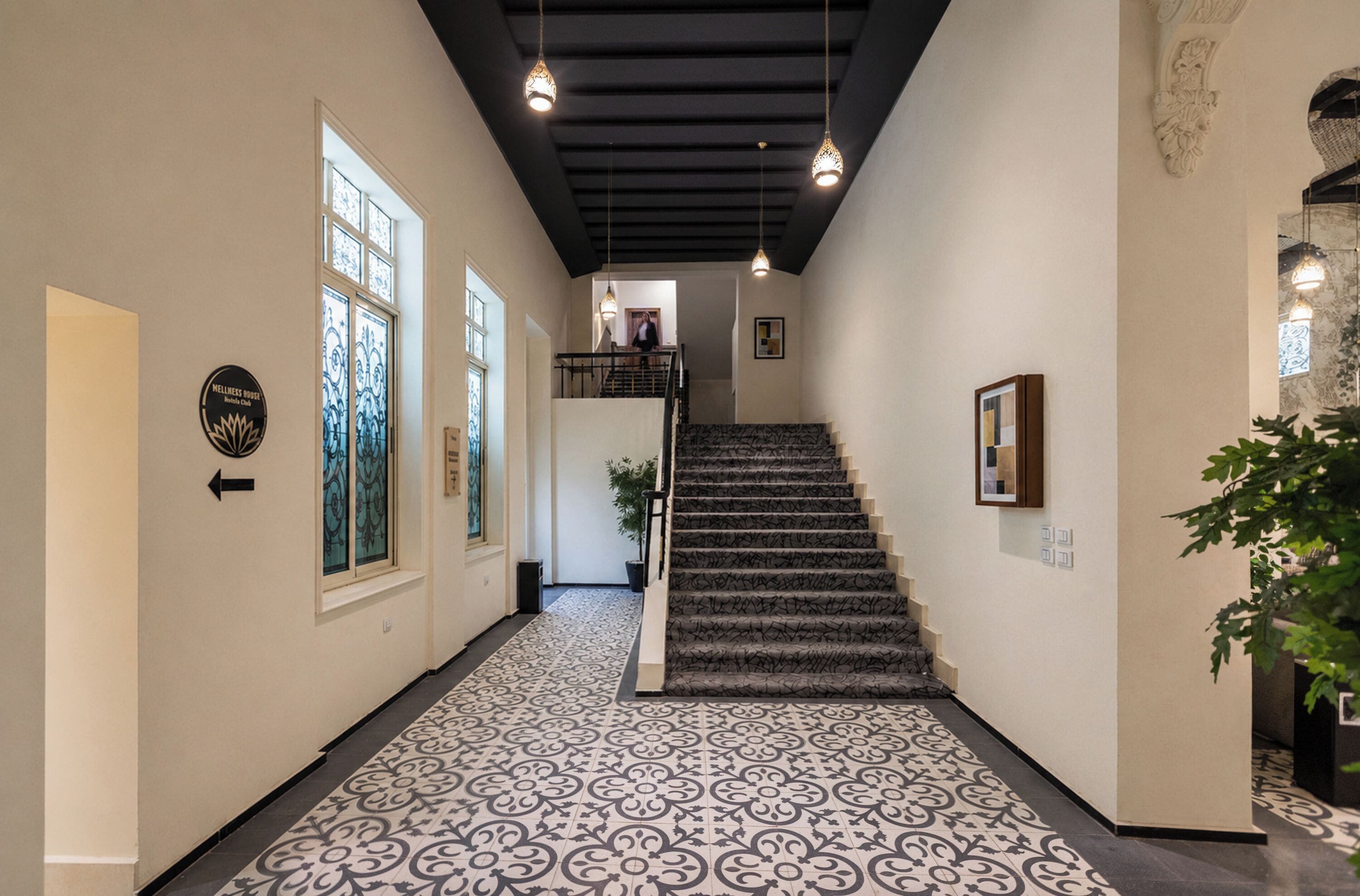 A hallway with patterned flooring, a staircase, and a door with a sign.