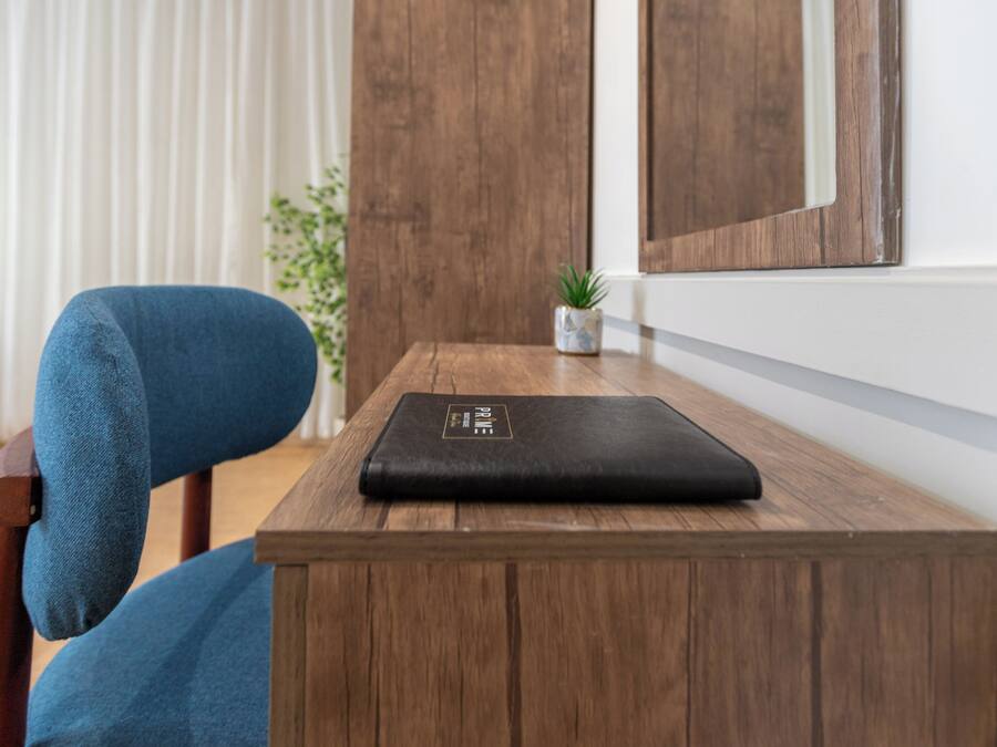 A wooden table with a black object on it, a blue chair, a small plant, and a wooden door in the background.