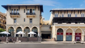 Un immeuble doté de nombreux balcons, d’une entrée couverte et d’une devanture de magasin avec une enseigne indiquant « SOLDES ».