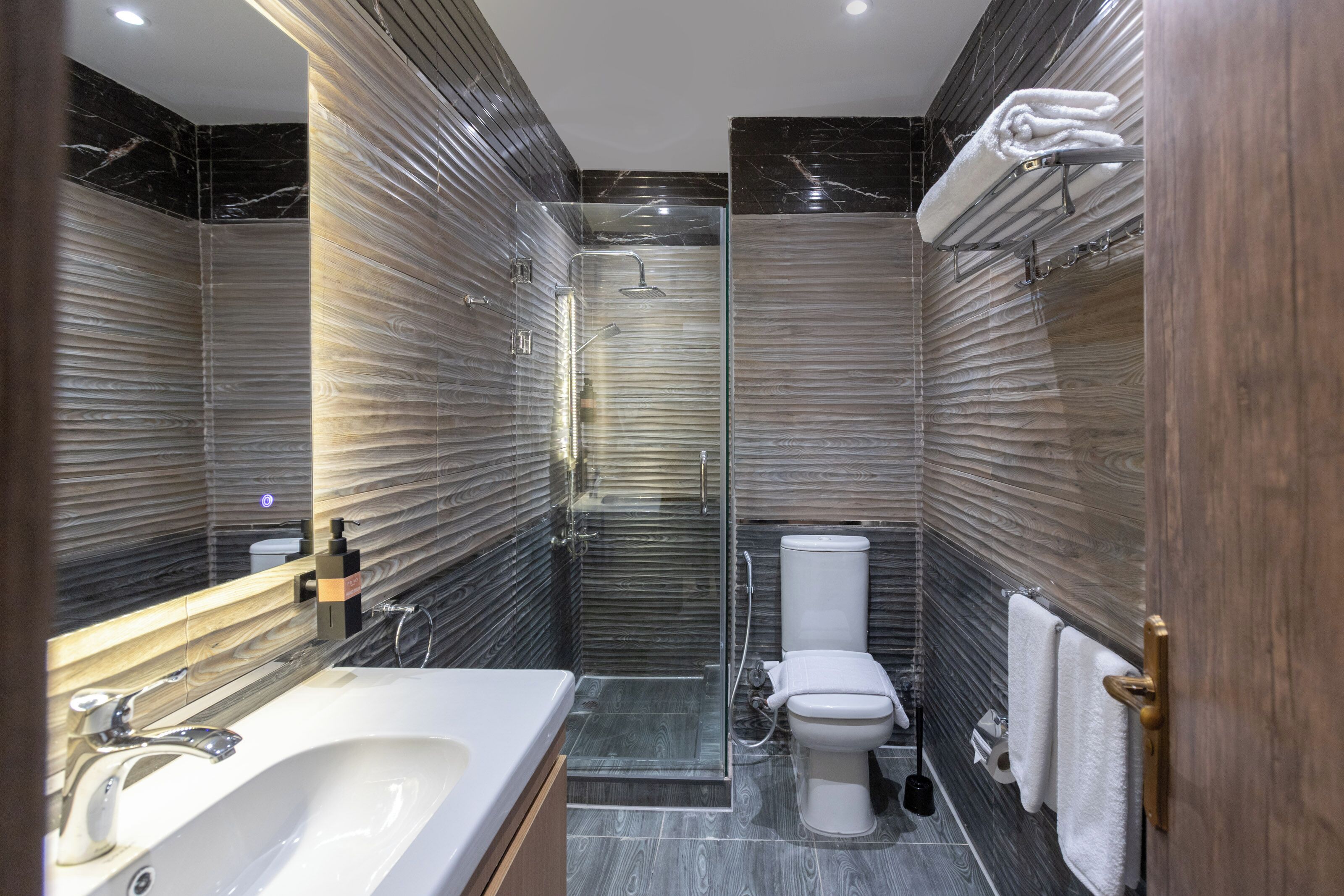 A modern bathroom with a glass-enclosed shower, a white sink, and a toilet.