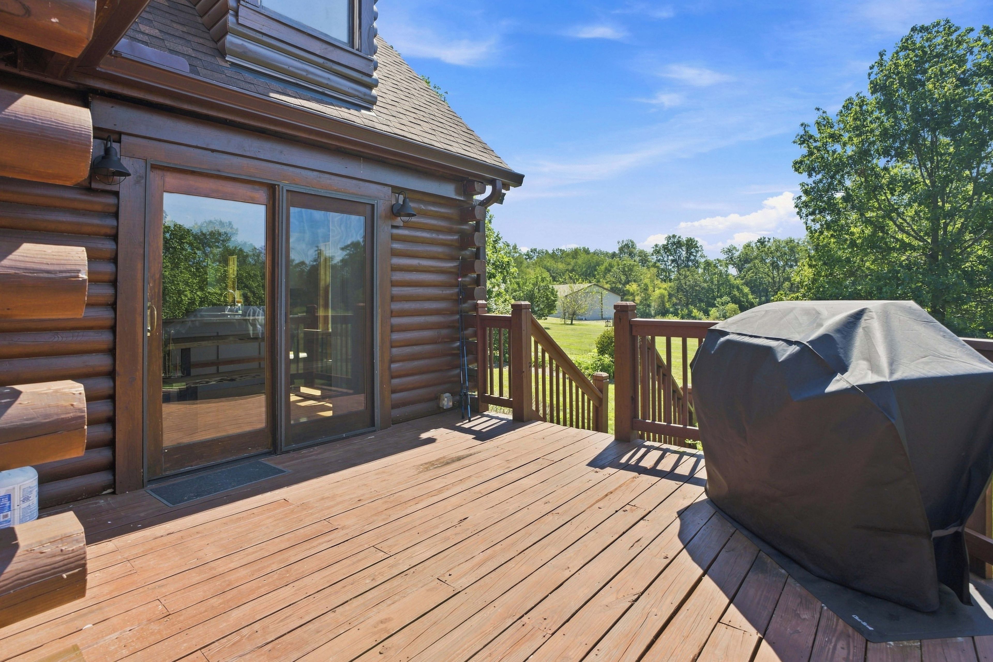Une terrasse en bois avec un barbecue couvert et une porte-fenêtre coulissante donnant sur une autre partie de la terrasse.